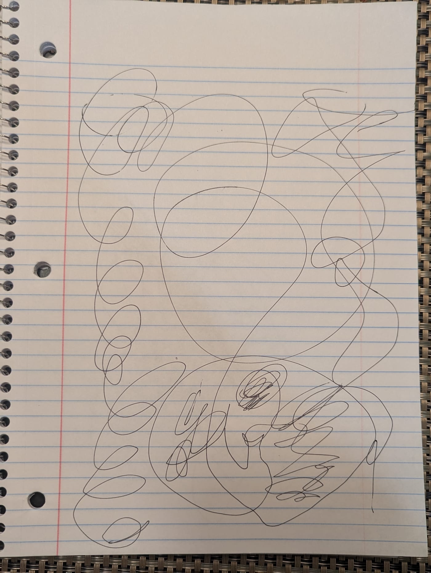 A sheet of lined notebook paper covered in looping pen lines: one large ring in the middle, a chain of small loops down the left side, and a tangle at the bottom